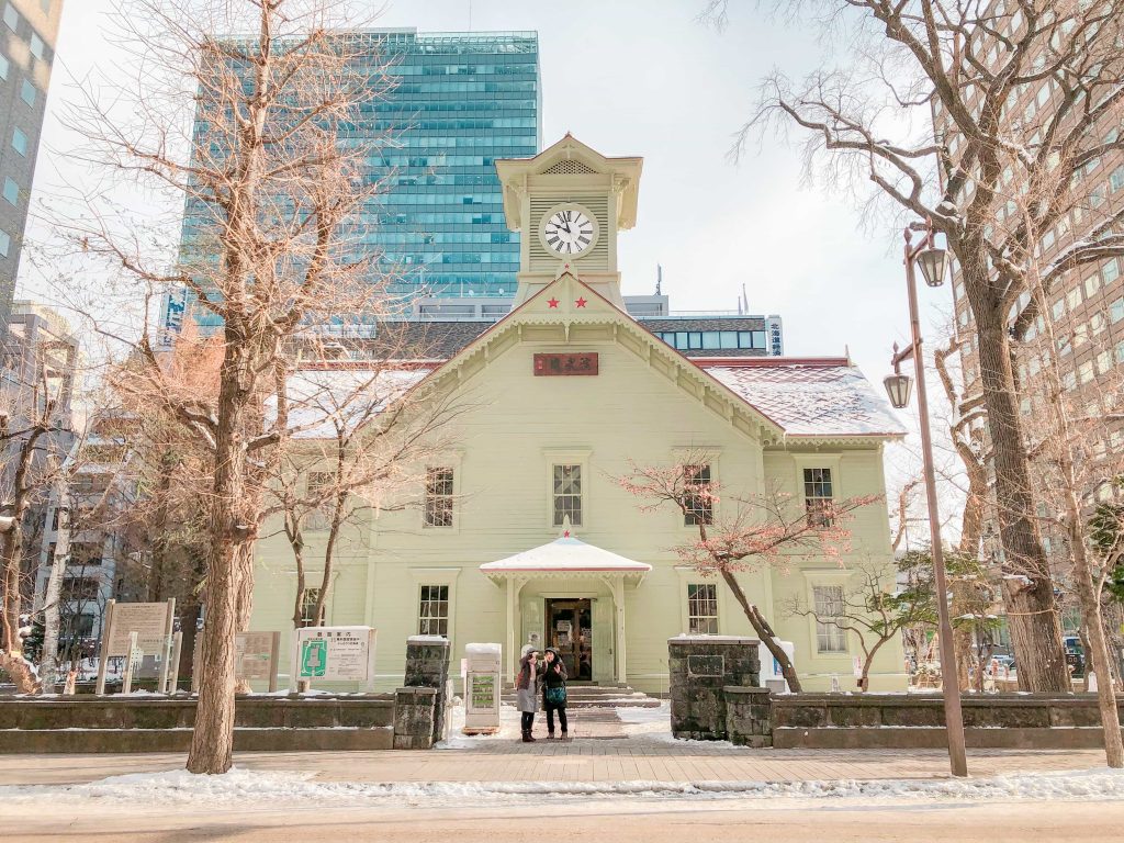 two tourists taking a selfie in front Sapporo Clock Tower