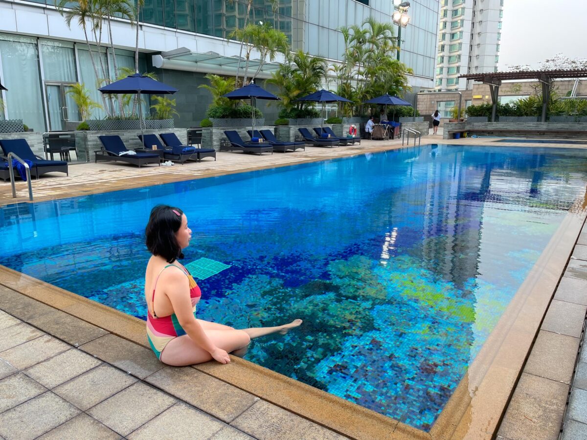 woman sitting on the edge of the pool at Novotel Citygate Hong Kong