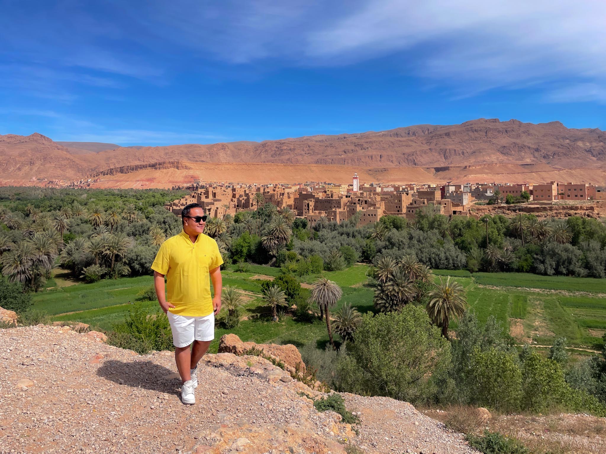 man standing on the edge of the cliff with views of the desert village